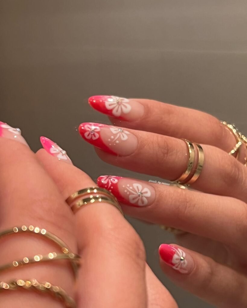 Bold hawaii nails ideas with hot pink ombre and white floral designs accented by rhinestones for a vibrant island-inspired manicure.