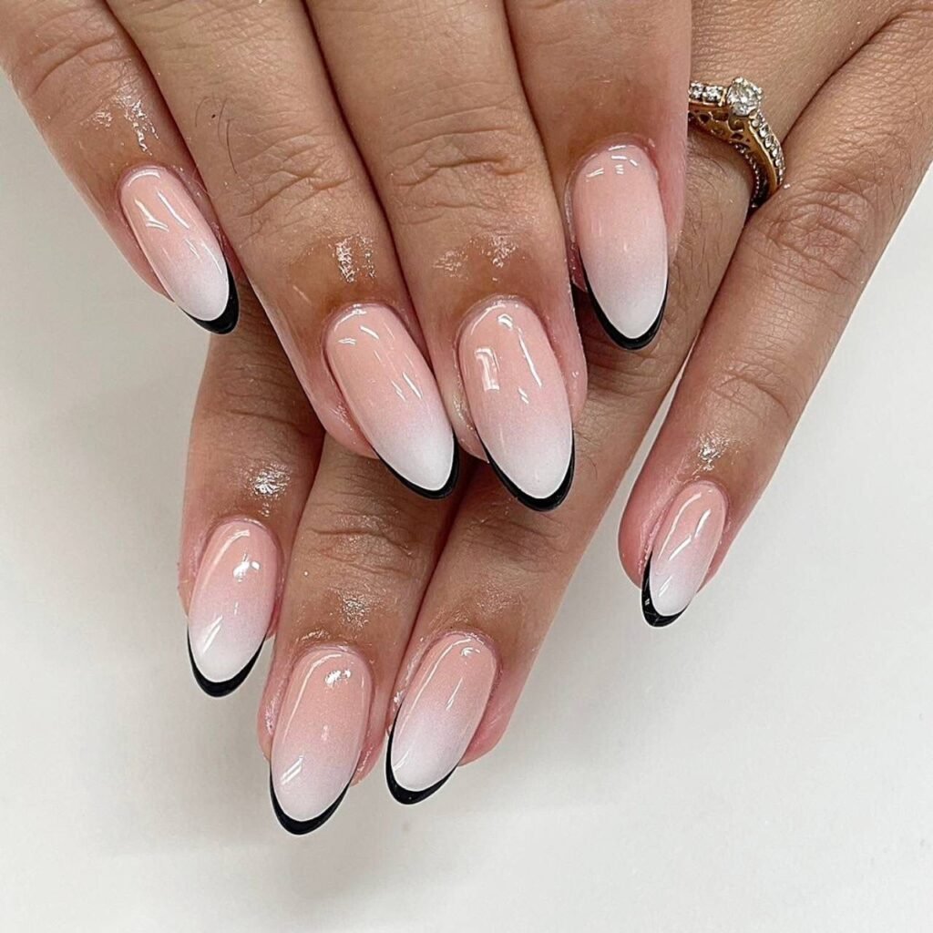 Elegant nude to white ombre May nails ideas with black tips on almond-shaped design for a chic look.