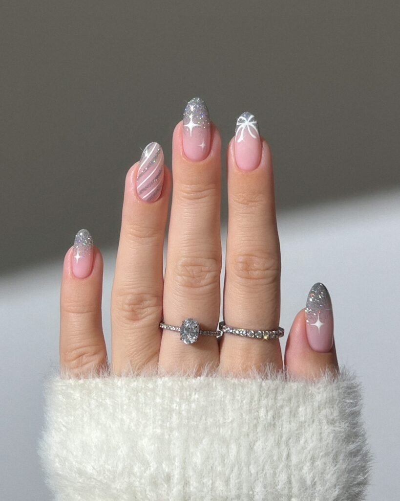 Hand with rings showing sparkling May nails ideas in pink ombré glitter with white stars and stripes for a playful vibe.