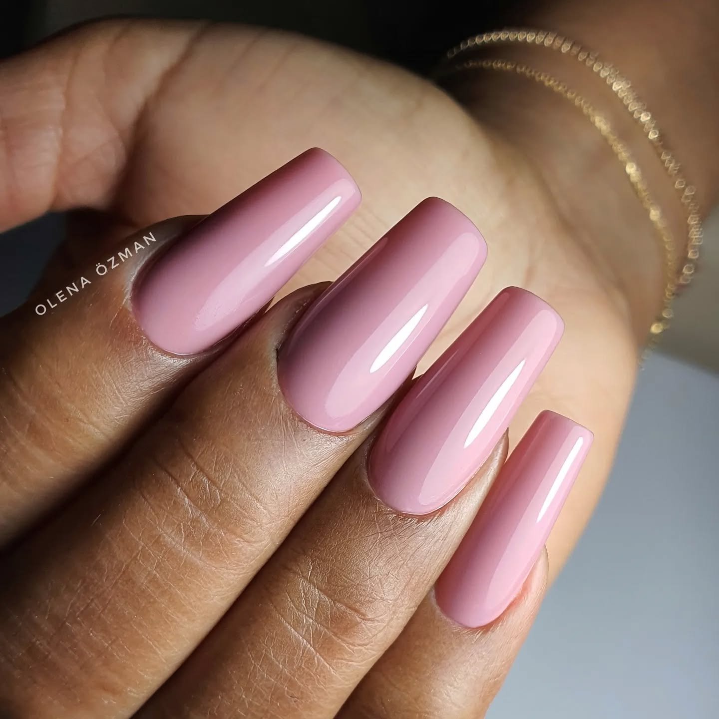 Close-up of a hand featuring long, glossy dusty pink nails in a coffin shape, showcasing elegant ballerina nails designs ideas.