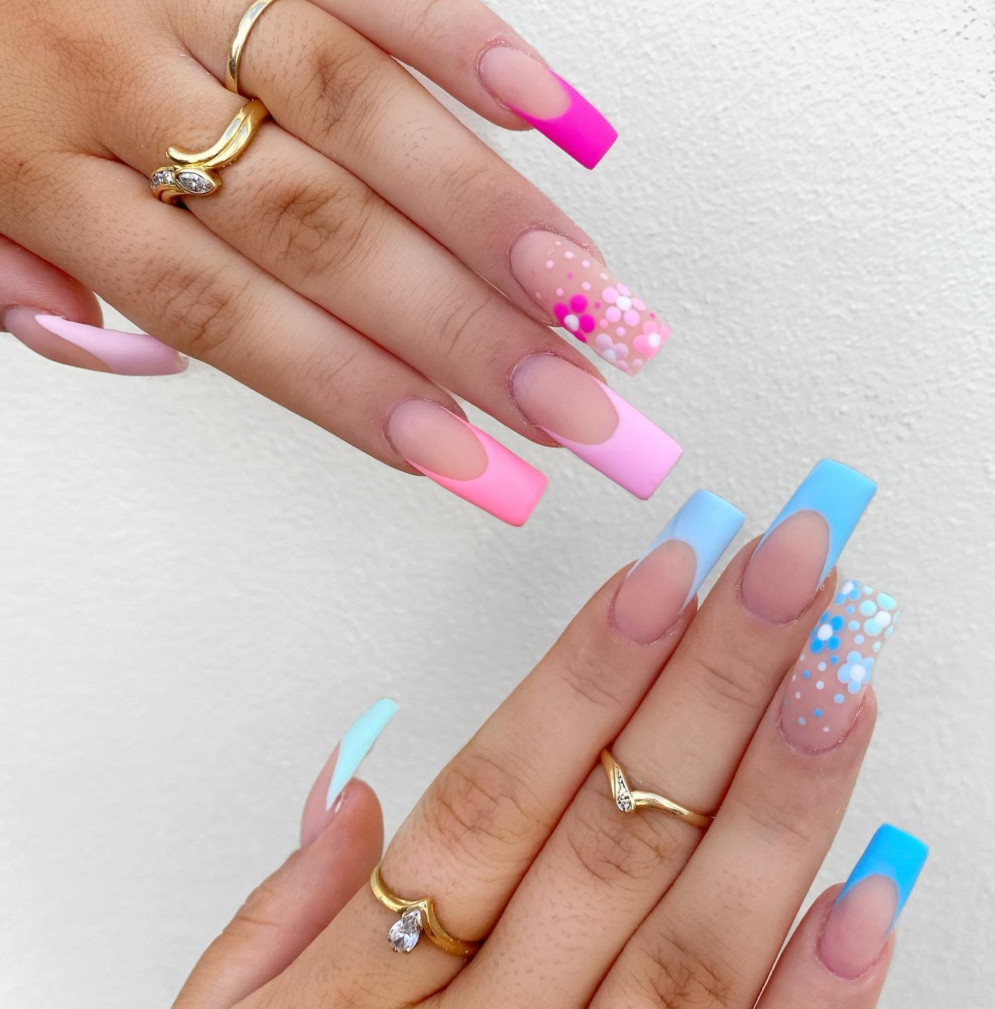 Two hands displaying long coffin nails with pink and blue French tips and polka dots, perfect for gender reveal nails ideas.