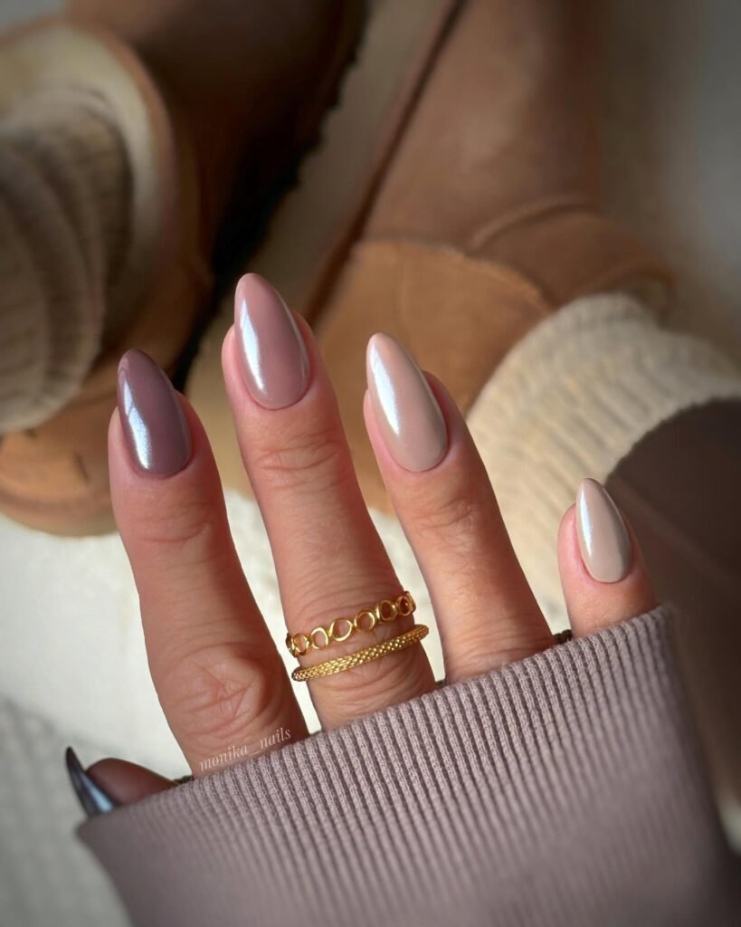 Pretty beige nails in almond shape styled with stacked gold rings