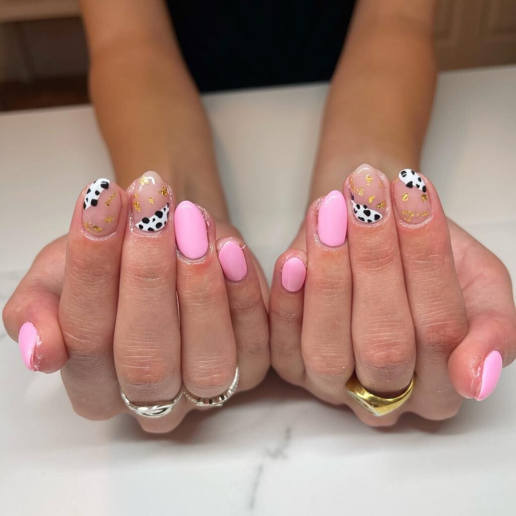 Pretty hands with soft pink nails featuring cow print and gold foil accents, perfect nashville nails ideas