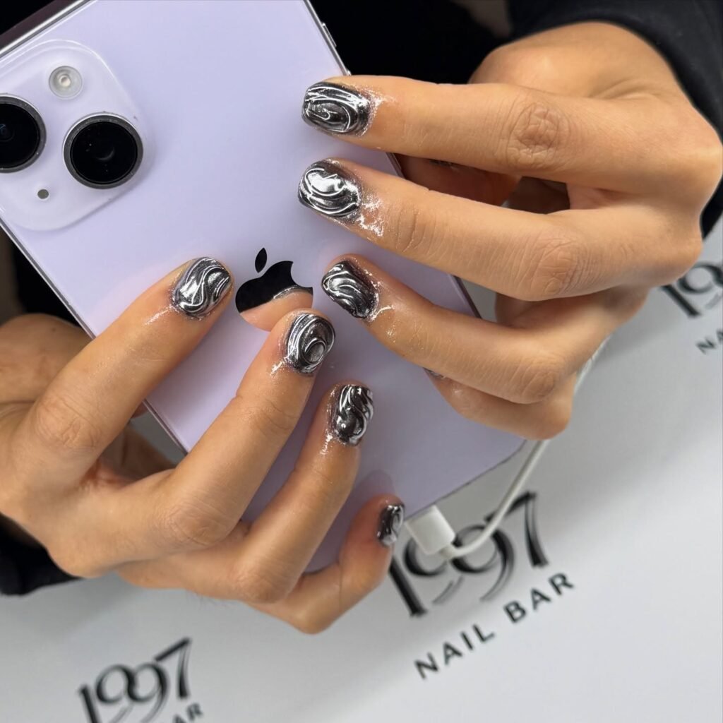 Shiny metallic silver swirl designs on natural nails showcasing aesthetic nails ideas