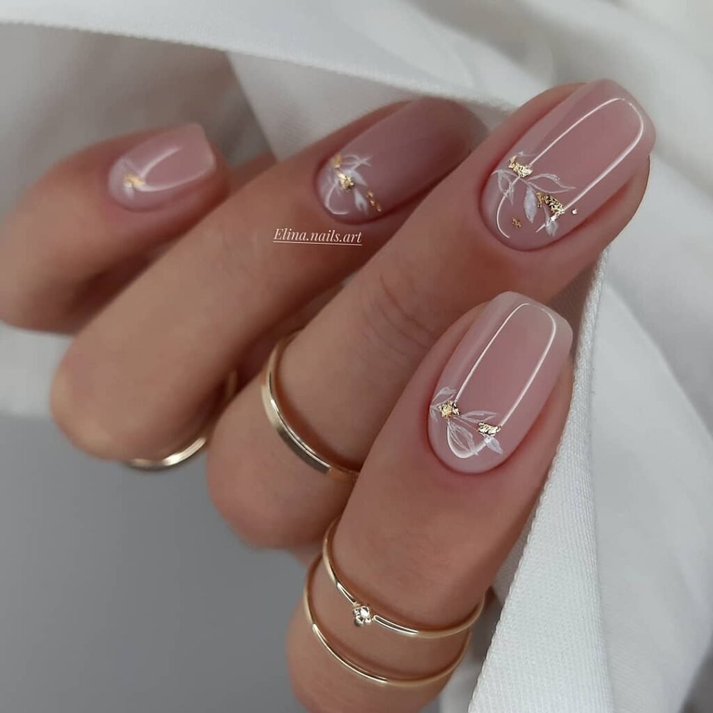 Delicate white floral line art and gold leaf details on soft pink clear nails ideas for a romantic everyday manicure