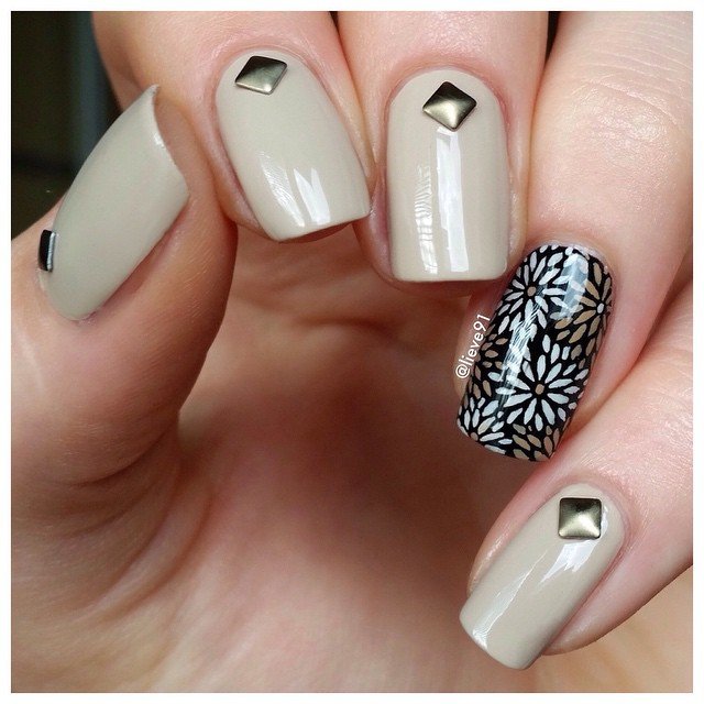 Creative beige nails decorated with silver pyramid studs and black floral pattern