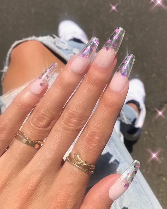 Long clear nails ideas decorated with floating purple hearts and iridescent glitter for a fun feminine vibe