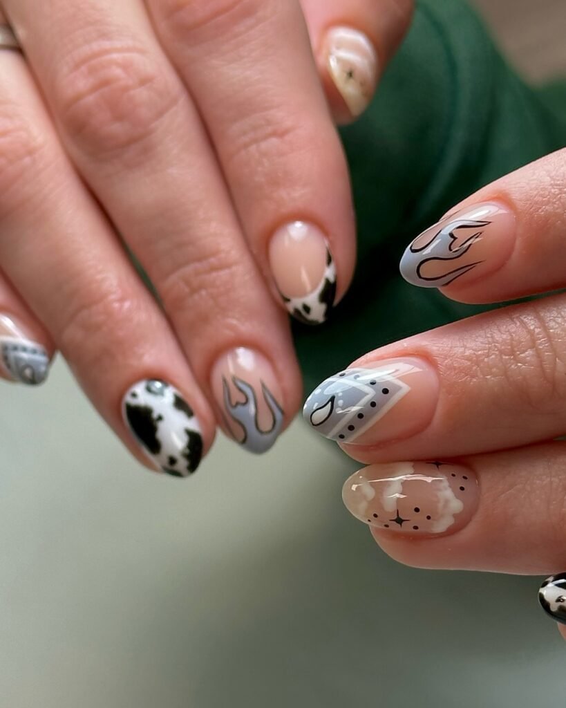 Detailed western-themed nails with cow print, flames and bandana designs as unique nashville nails ideas