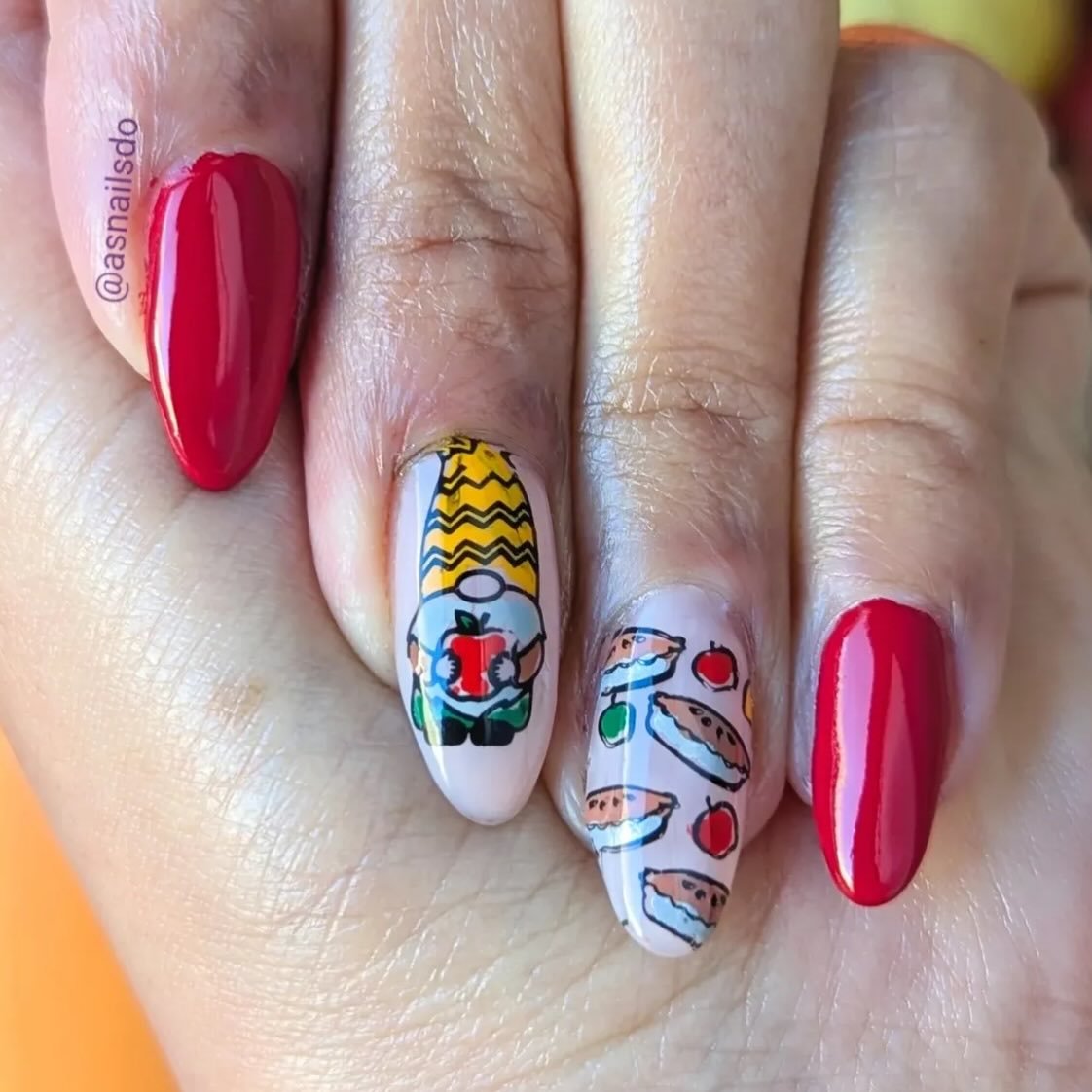 Cute hand-painted gnome holding an apple with watermelon slices and picnic snacks on these fun painted nails ideas