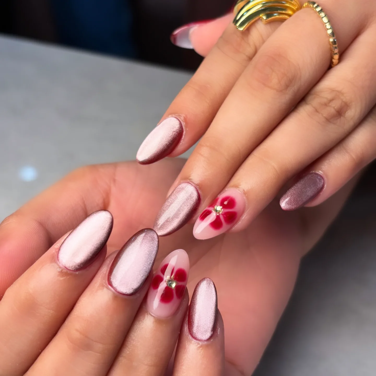 Soft pink chrome nails with red floral and crystal details showcasing aesthetic nails ideas