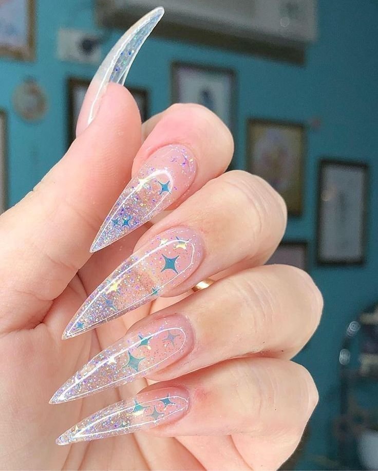 Dreamy extra-long stiletto clear nails ideas covered in blue and gold stars with sparkling glitter