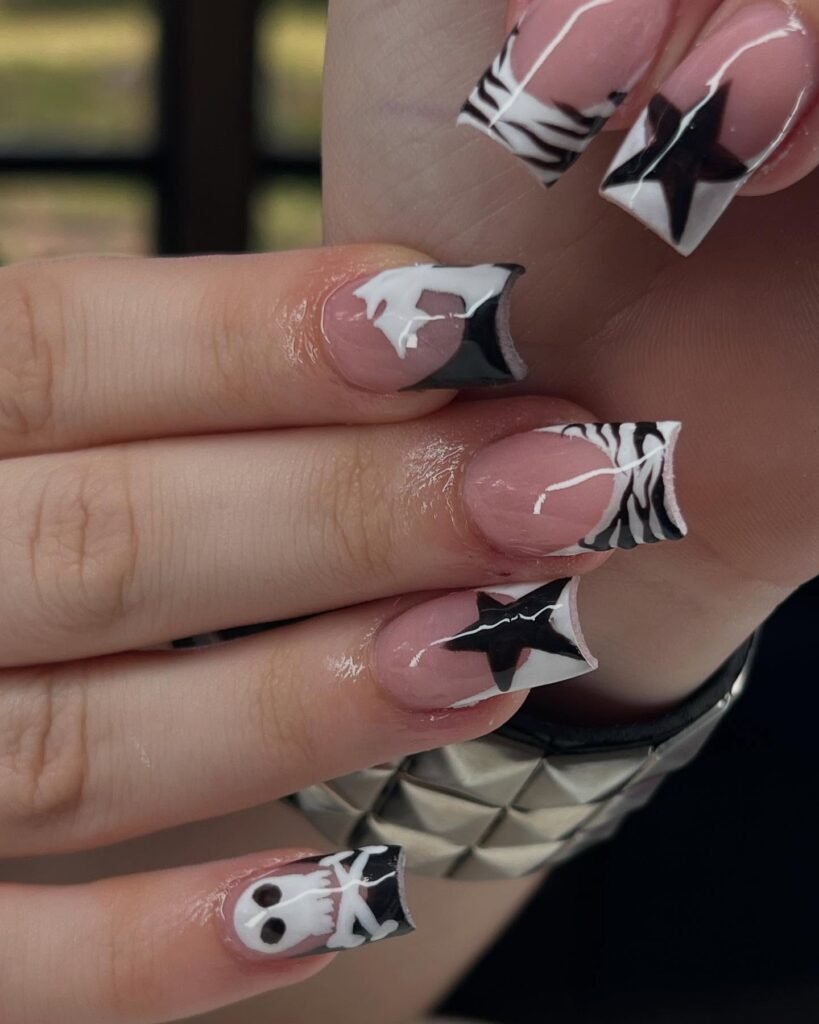 Get inspired by these creative emo nails ideas featuring pink bases with black-and-white zebra stripes, bold stars, and spooky skull designs on coffin-shaped nails