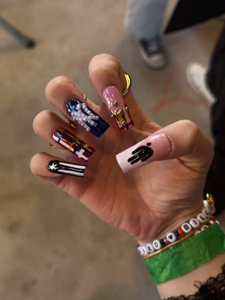 Fun pink and blue graphic billie eilish nails ideas with pearl cross, plaid patterns and the iconic black figure silhouette