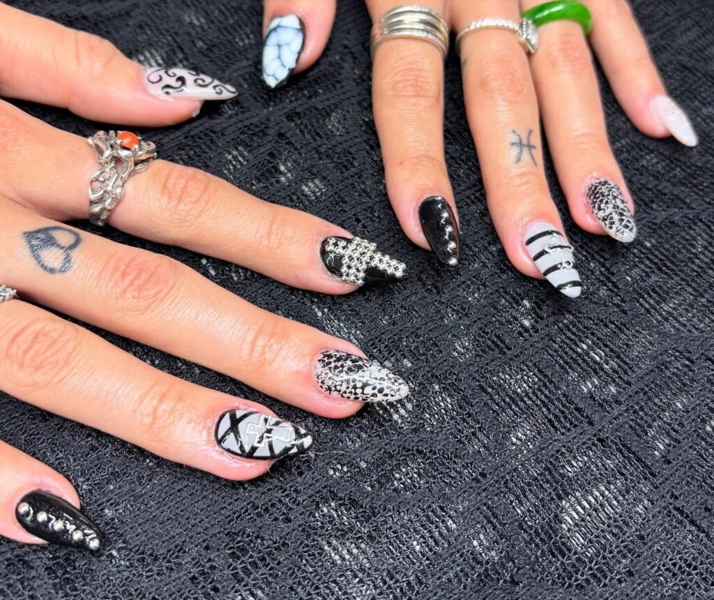 Get inspired by these intricate emo nails ideas showcasing black-and-white patterns, metal studs, cracked textures, and swirling gothic designs