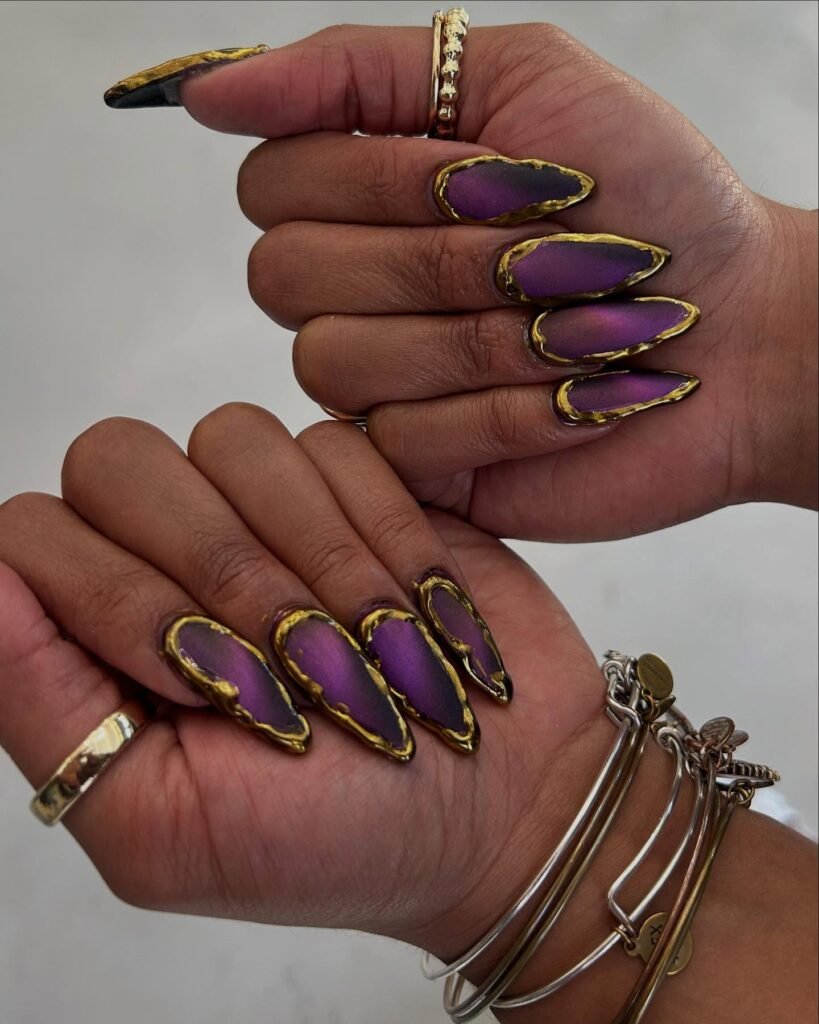 Long almond purple nails with gold foil edges showcasing luxurious Mardi Gras nails ideas