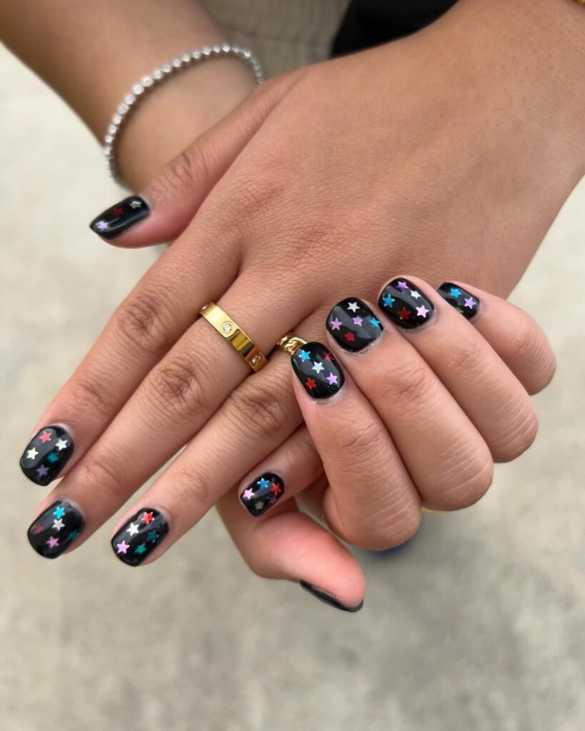 Chic olivia rodrigo nails ideas featuring black nails covered in multicolored stars