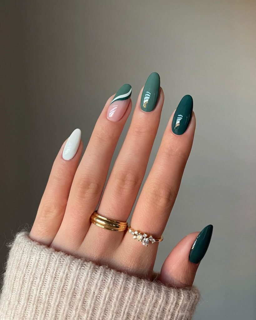 Sophisticated dark green nails with white swirl accents and gold foil in these luxe painted nails ideas