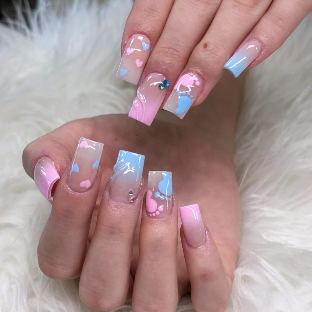 Beautiful ombre pink and blue gender reveal nails ideas decorated with hearts and baby footprints
