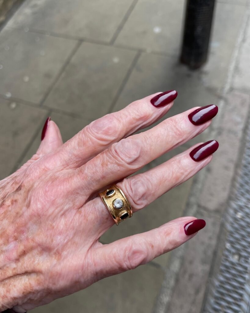 Sophisticated deep burgundy senior nails ideas on a mature hand with a classic gold ring