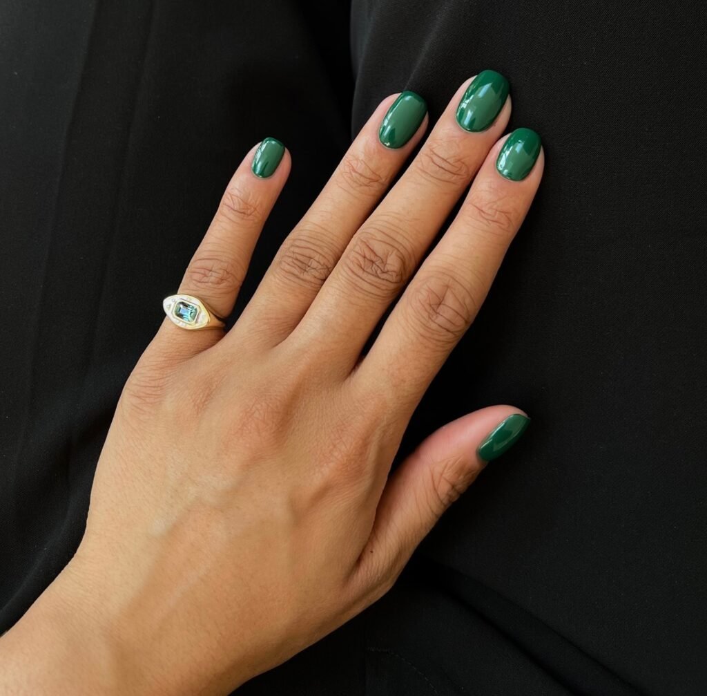 Chic forest green senior nails ideas paired with an elegant gold signet ring