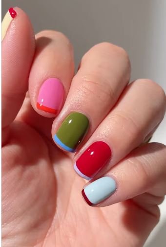 A hand with long almond nails showing a sheer nude base with soft pastel tips, highlighting a delicate style of **two color french tip nails