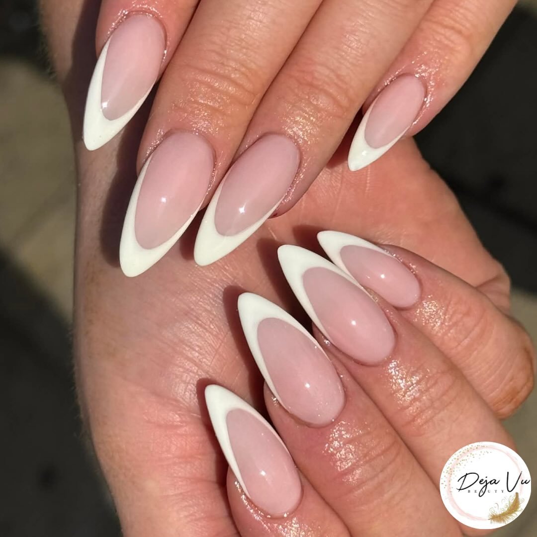A pair of hands displaying elegant, almond-shaped long french tip nails with a soft pink base and crisp white tips.