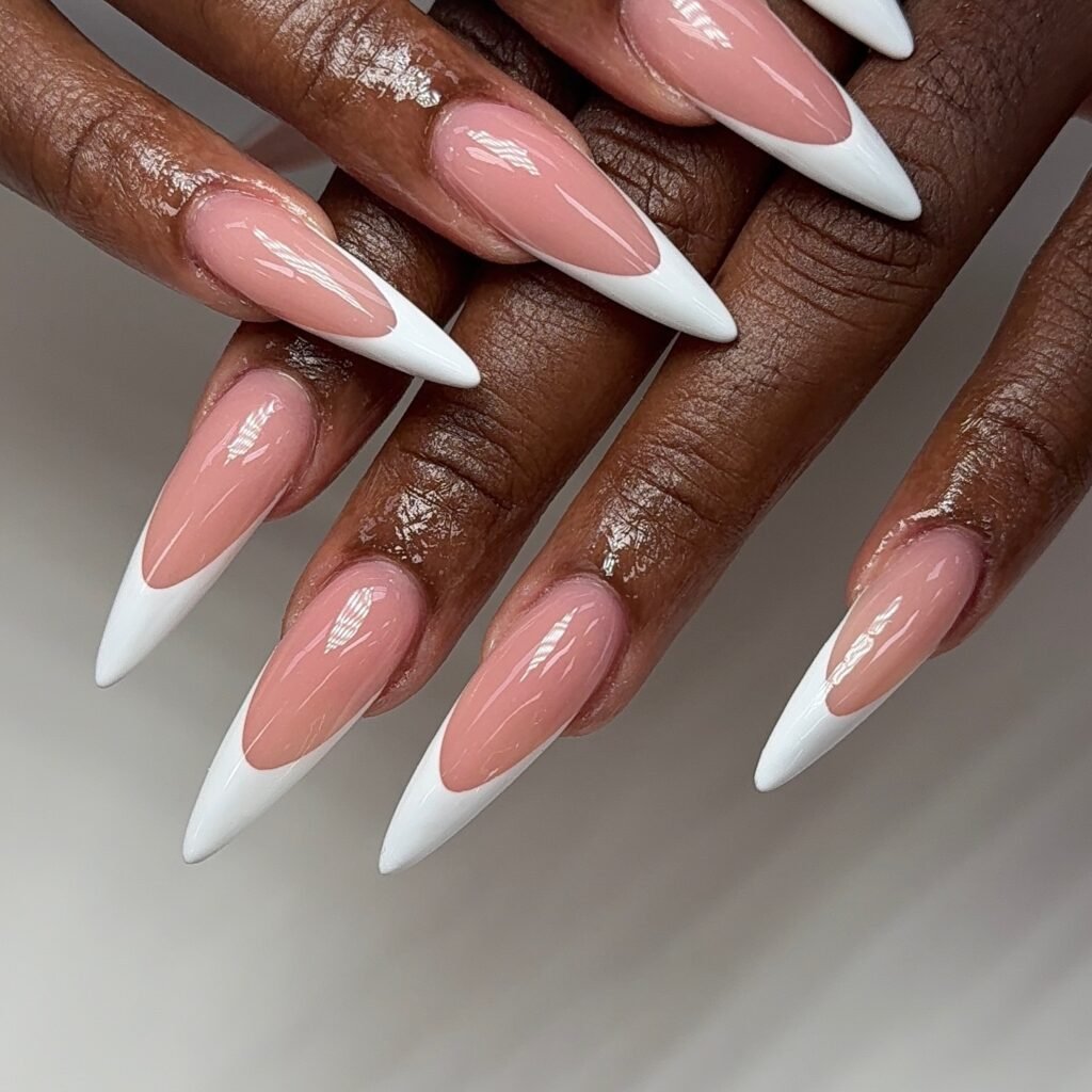 Close-up of hands featuring long, glossy almond French tip nails with a soft nude-pink base and crisp white tips.